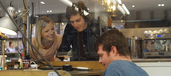 Couple watching goldsmith making ring in workshop