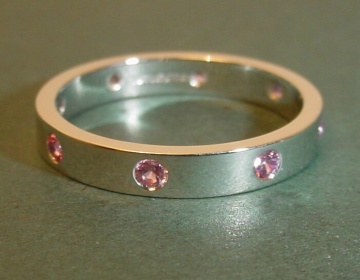 An 18ct white gold eternity ring with 8 invisibly set pink sapphires.