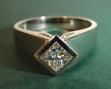 Wide 18ct white gold engagement ring
with a princess cut 0.56ct diamond 