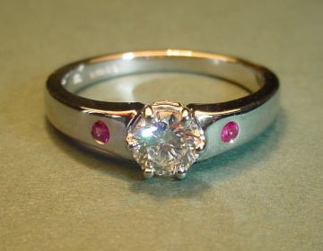 A platinum engagement ring with a diamond and rubies