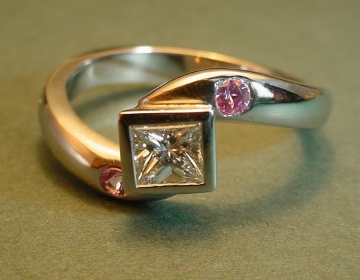 A white gold engagement ring set with a diamond and pink sapphire