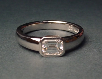 Platinum engagement ring with an emerald cut diamond.