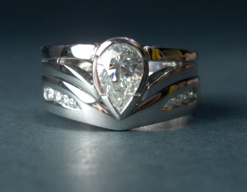 Bespoke platinum wedding ring fitted around pear engagement ring