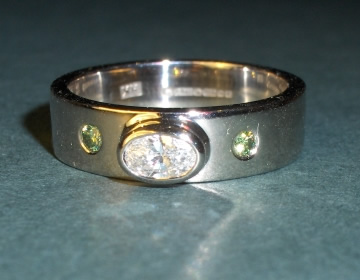 Bespoke engagement ring with oval diamond and green heat-treated diamonds.