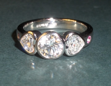 Bespoke platinum and diamond ring with heart shaped shoulder diamonds.