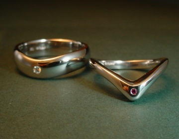 A platinum wedding ring pair with a diamond and pink sapphire