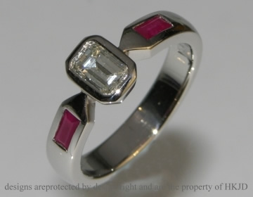 Bespoke platinum engagement ring with an emerald cut central diamond and 2 baguette cut rubies. 