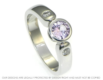 18ct white gold engagement ring with a central pink sapphire and side diamonds.