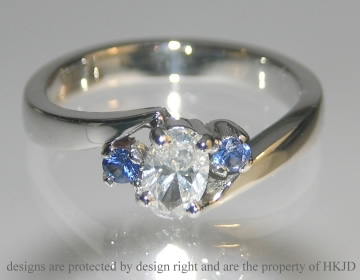 Platinum engagement ring incoporating customers own oval cut 0.47ct diamond and two new brilliant cut blue sapphires.