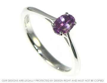 An 18ct white gold and deep pink sapphire solitaire engagement ring