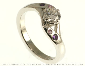 Platinum swirl style engagement ring with diamond and amethyst and lilac sapphires. 