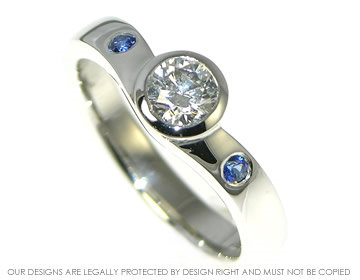 Platinum engagement ring with a diamond and two sapphires.