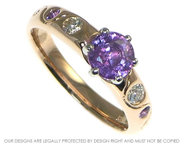 A 9ct rose gold and platinum engagement ring incorporating a 6.7mm 1.42ct purple sapphire,  two 3mm brilliant cut H SI diamonds 0.22ct and two 2mm brilliant cut amethyst.