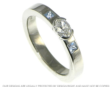 Bespoke platinum engagement ring with an oval cut diamond and a pair of sapphires