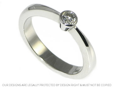 Delicate platinum engagement ring with a tapered shank and a brilliant cut diamond. 