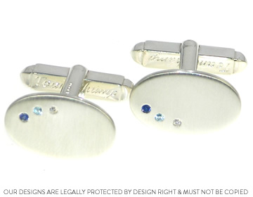 A silver pair of cufflinks with complimenting stones