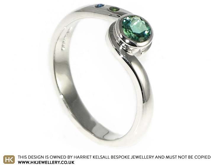 Twist style engagement ring with a central crisp green tourmaline