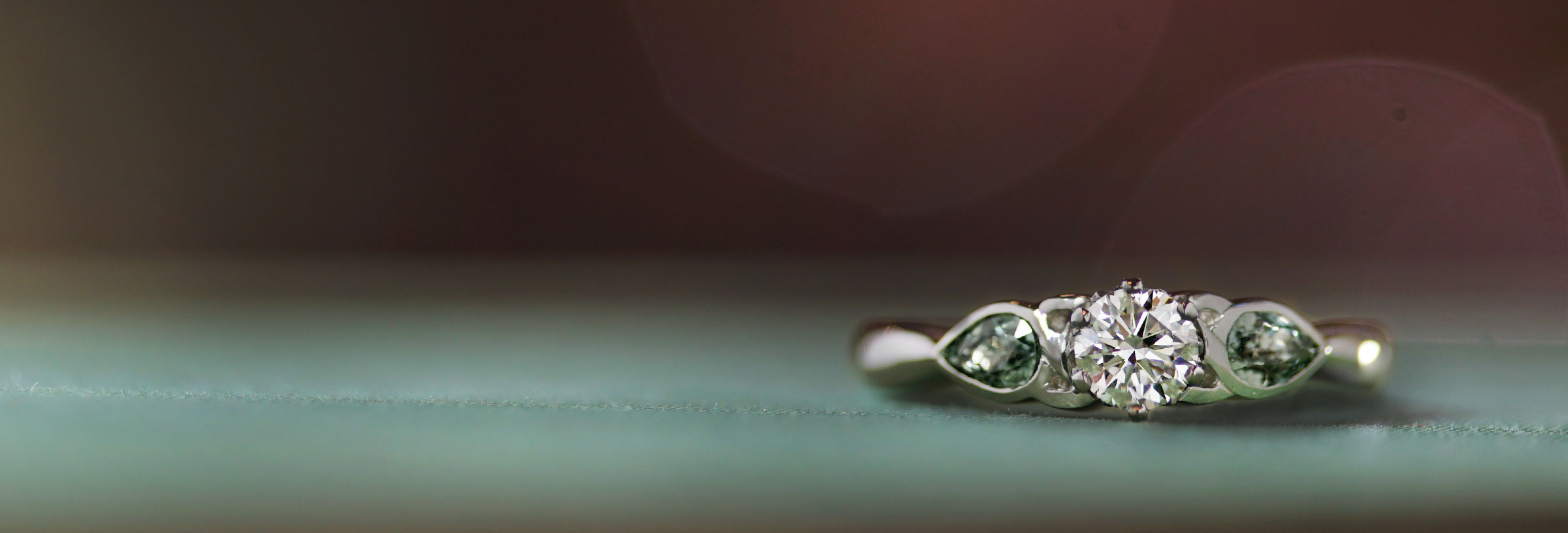 platinum-trilogy-engagement-ring-with-diamond-and-green-sapphires