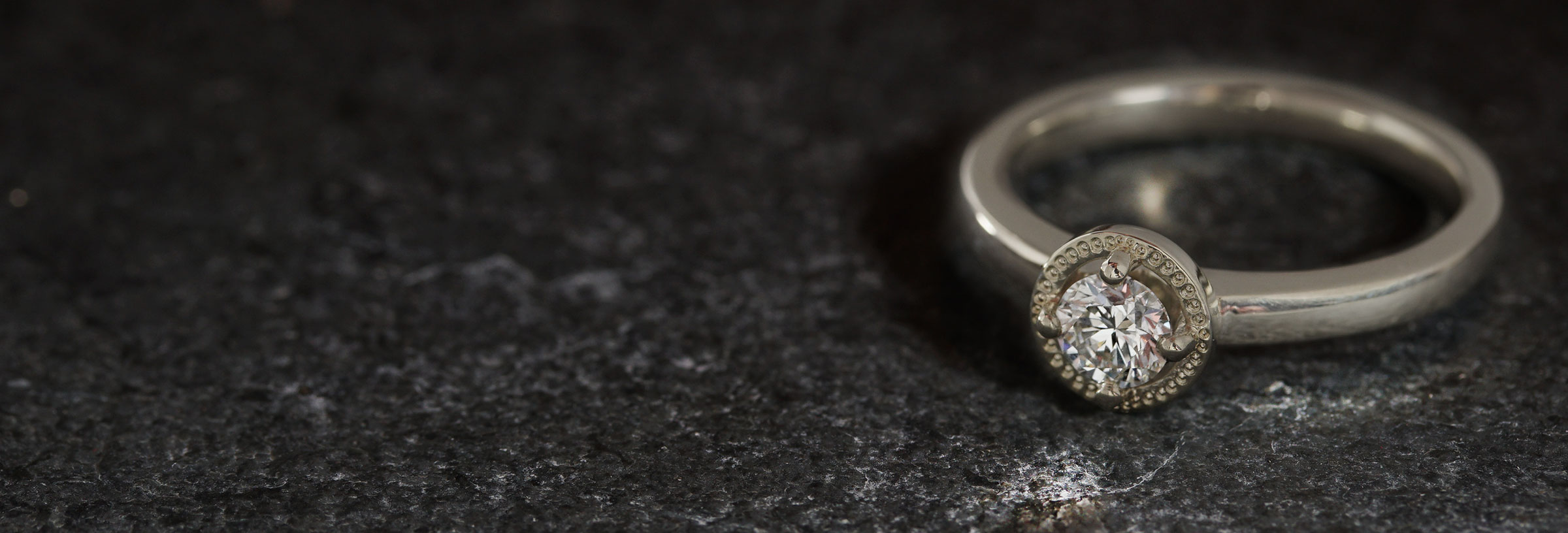white-gold-and-diamond-engagement-ring-with-graining-detailed-halo